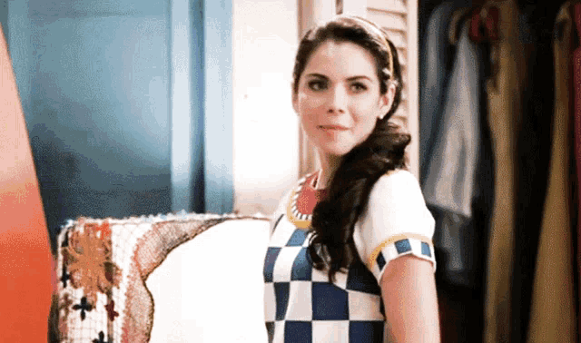 a woman in a blue and white checkered dress is standing in front of a closet