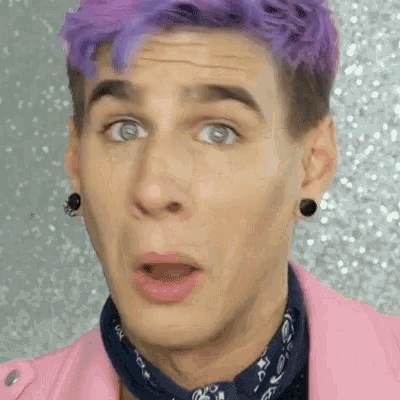 a man with purple hair is wearing a pink jacket and a blue bandana and making a surprised face .