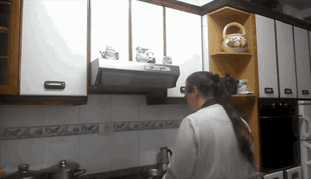 a woman standing in a kitchen with a basket on the shelf that says ' honey ' on it