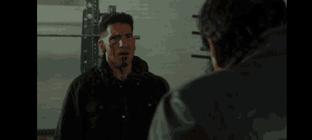 two men are standing next to each other in a gym and talking .