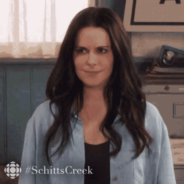 a woman with long dark hair is wearing a blue shirt and a black shirt .