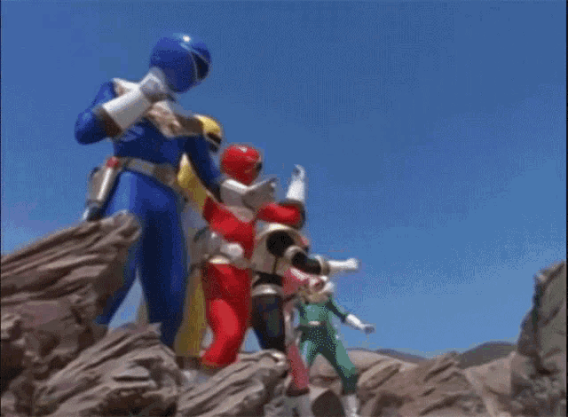 a group of power rangers standing on top of a rocky hillside