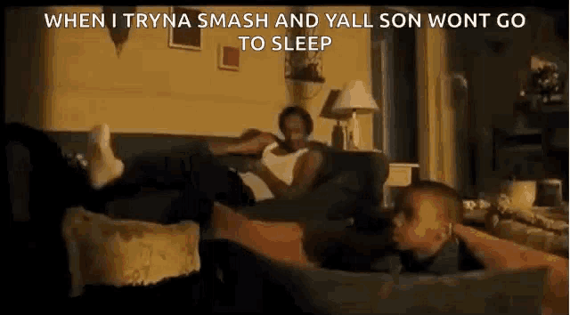 a man is laying on a couch with a baby on his lap .
