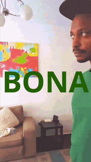 a man in a green shirt is standing in front of a wall that says bona