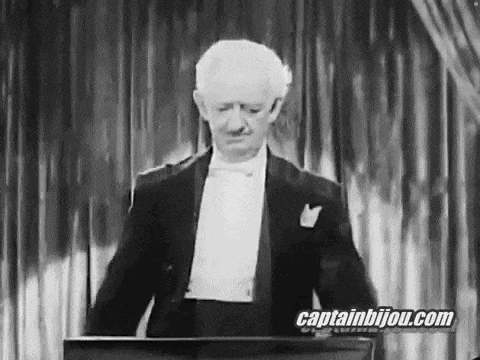 a man in a tuxedo and bow tie is standing in front of a podium .