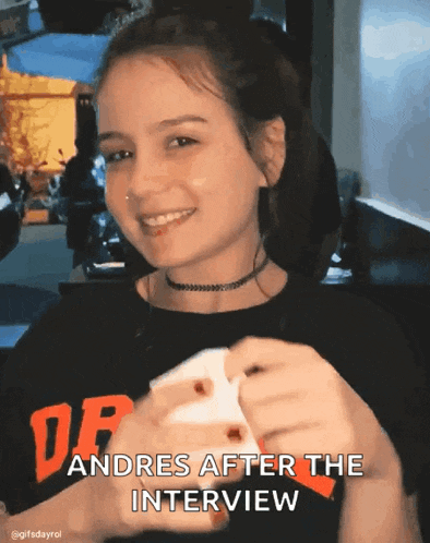 a girl wearing a black shirt that says andres after the interview is smiling