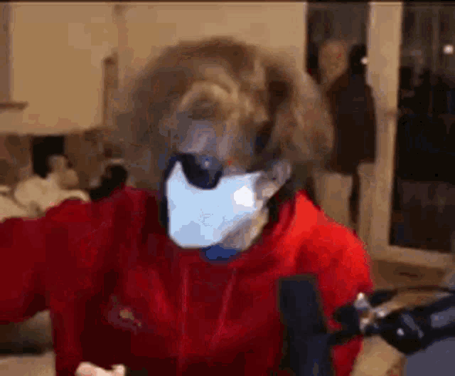 a man wearing a mask and sunglasses is sitting in front of a microphone .