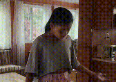 a young girl is standing in a room in a kitchen .