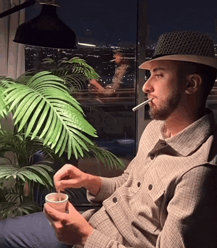 a man in a hat is smoking a cigarette