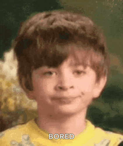 a young boy in a yellow shirt is looking bored