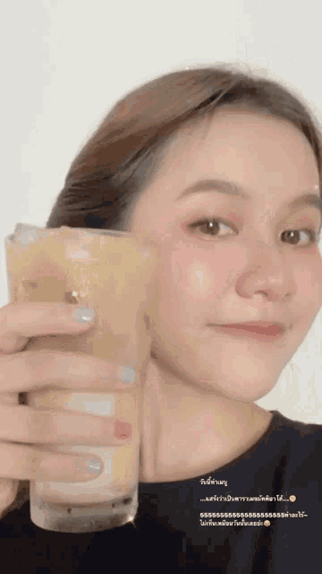 a woman is holding a glass of iced coffee in front of her face ..