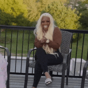 a woman with blonde hair is sitting in a chair on a balcony