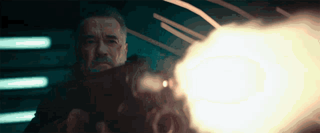 arnold schwarzenegger is holding a gun that is pointed at the camera