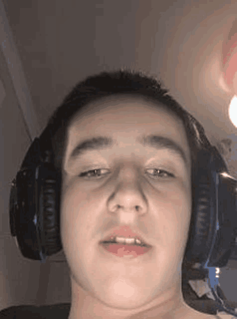 a young boy wearing headphones is making a funny face .