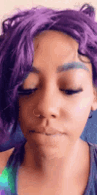 a close up of a woman with purple hair and blue eyebrows .