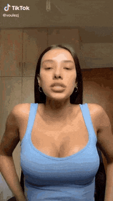 a woman is wearing a blue tank top with a very large breast