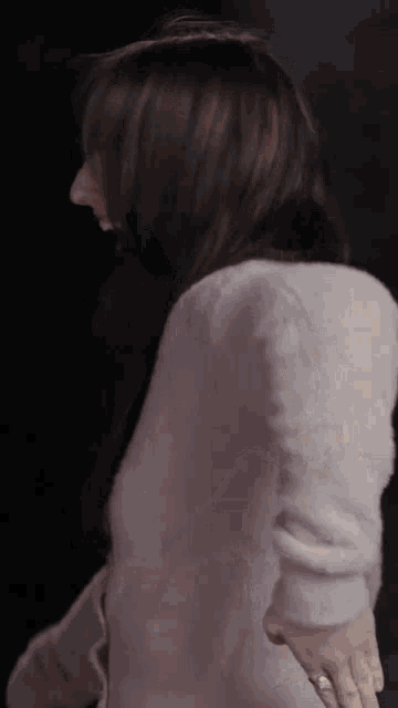 a woman in a pink sweater is standing in a dark room .