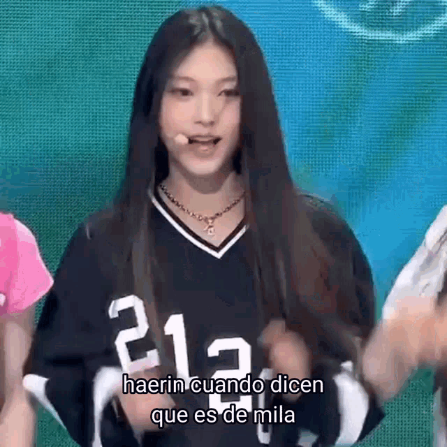 a girl with long hair is wearing a black jersey with the number 212 on it .