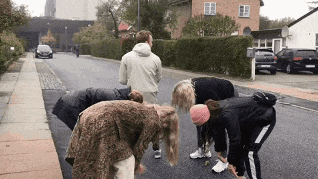 a group of people standing on the side of a road with one wearing a pink beanie