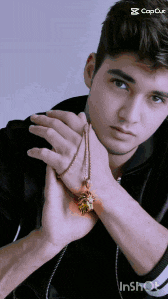 a young man is holding a necklace with a pine cone pendant on it
