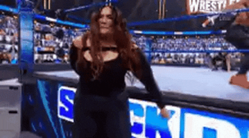 a woman is standing on a stage in a wrestling ring in front of a crowd .