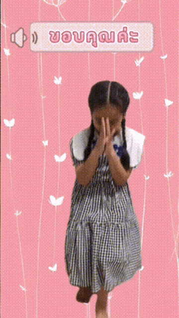 a girl in a plaid dress is praying in front of a pink background with hearts