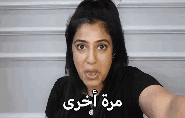 a woman wearing a black shirt has arabic writing on her face