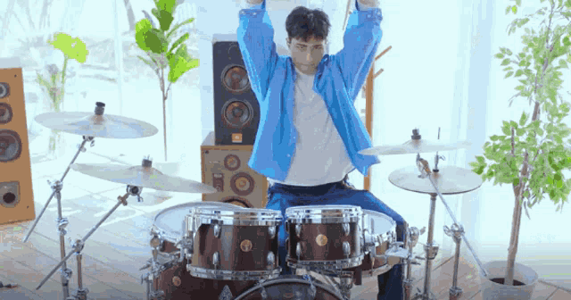 a man in a blue shirt is playing drums in a room
