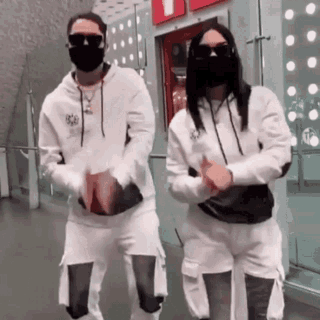a man and a woman wearing face masks and sunglasses are dancing together .