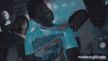 a man in a white shirt is standing in front of a crowd with make a gif.com on the bottom right
