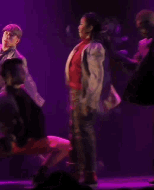 a group of people are dancing in front of a purple background