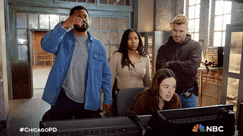 a group of people standing around a computer monitor with nbc written on the bottom right