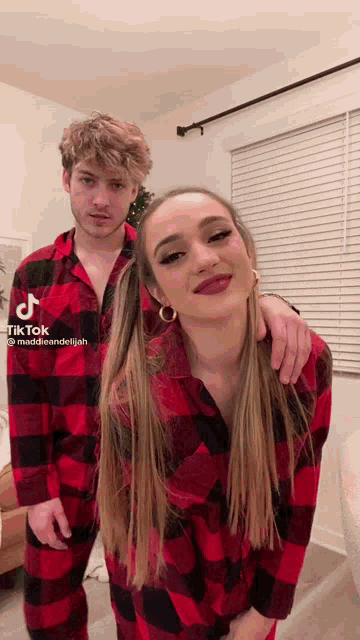 a man and a woman wearing plaid pajamas are standing next to each other
