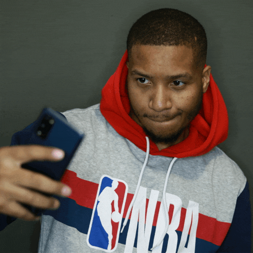 a man in a nba hoodie takes a selfie with his phone