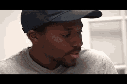 a man wearing a baseball cap and a gray shirt is looking down .