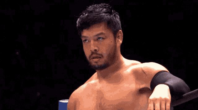a man without a shirt is leaning on a blue ring post