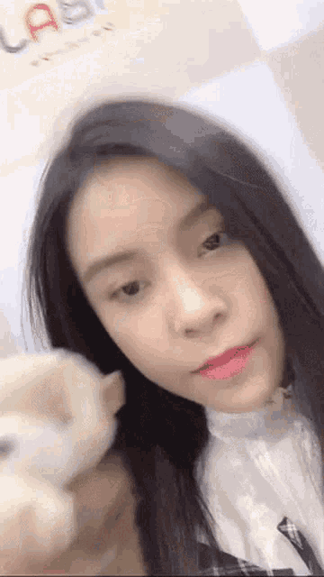 a woman with long black hair is holding a stuffed animal and looking at the camera .