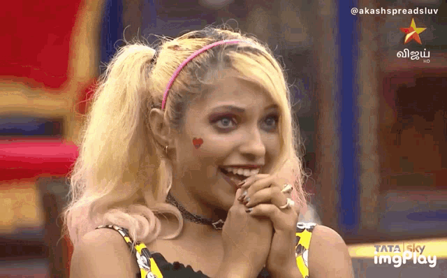 a woman with blonde hair and blue eyes is smiling in front of a tata sky logo
