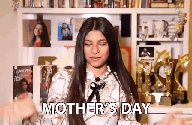 a woman says mother 's day in front of a shelf full of trophies