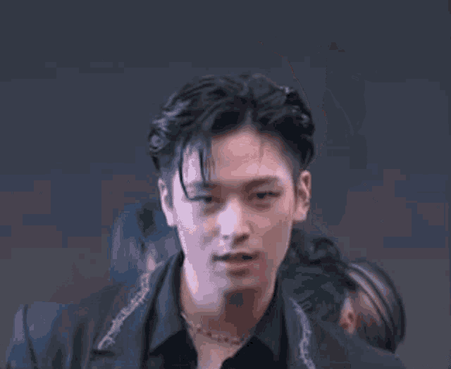 a close up of a man wearing a black jacket and a black shirt with his mouth open .