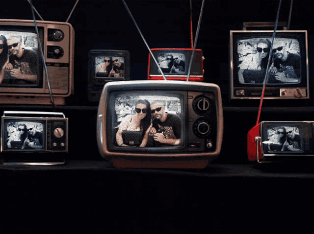 a couple posing for a picture on a television screen with a few other televisions