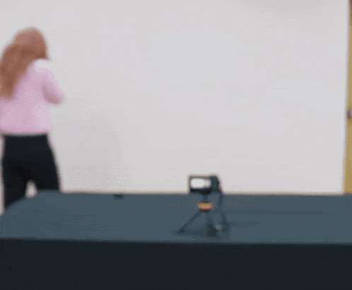 a woman in a pink shirt is standing in front of a white board