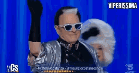 a man wearing sunglasses and a silver jacket stands in front of a blue screen with the words viperissima on it