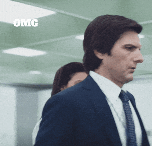 a man in a suit and tie is standing next to a woman and says omg