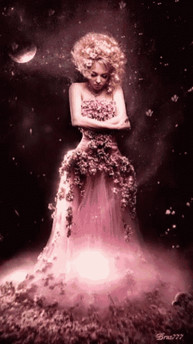 a woman in a pink dress made of flowers is standing in a dark room
