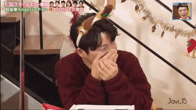 a man with a reindeer headband covering his mouth
