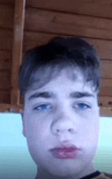 a young boy with blue eyes is making a funny face .