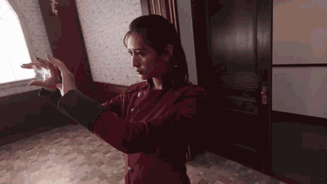 a woman in a red jacket is standing in a hallway