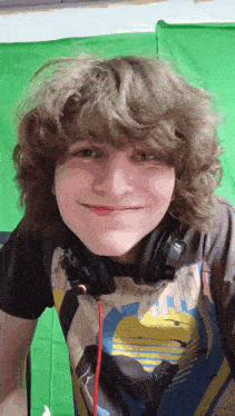 a young man with curly hair wearing headphones and a shirt that says ' nintendo ' on it