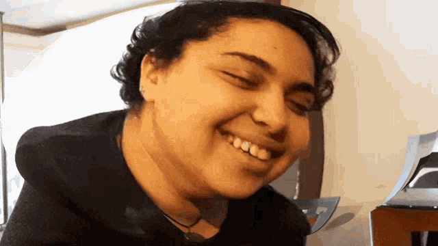 a woman is smiling with her eyes closed and her teeth visible